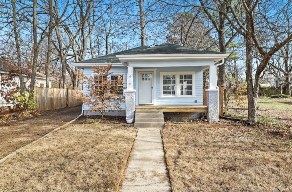 a small white house with a sidewalk in front of it