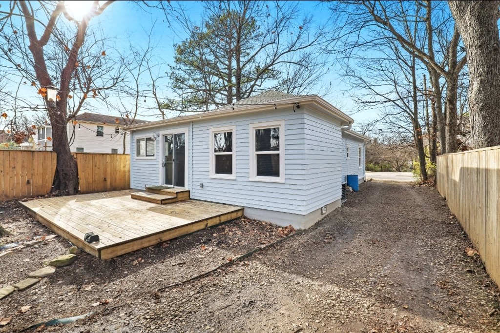 a blue house with a wooden deck and a wooden fence