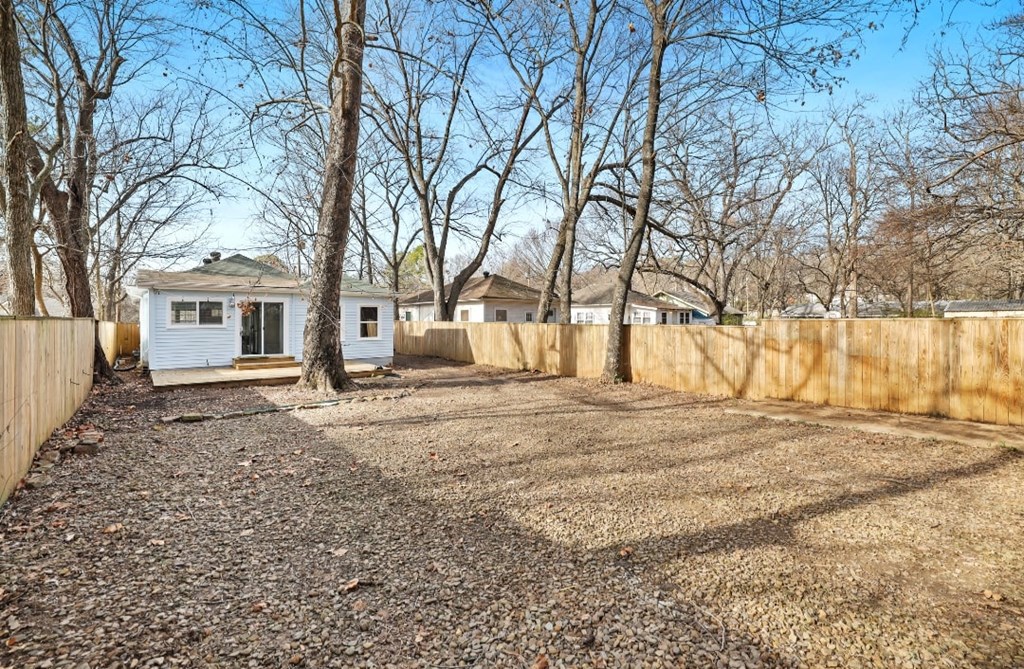 a backyard with a fence and a tiny house next to a gravel driveway
