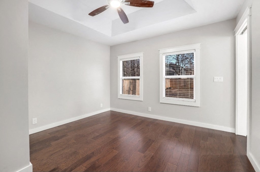 an empty living room with wood floors and a ceiling fan