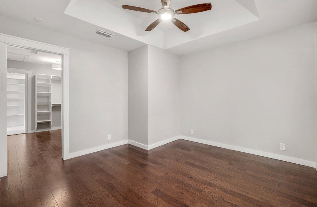 an empty living room with wood floors and a ceiling fan