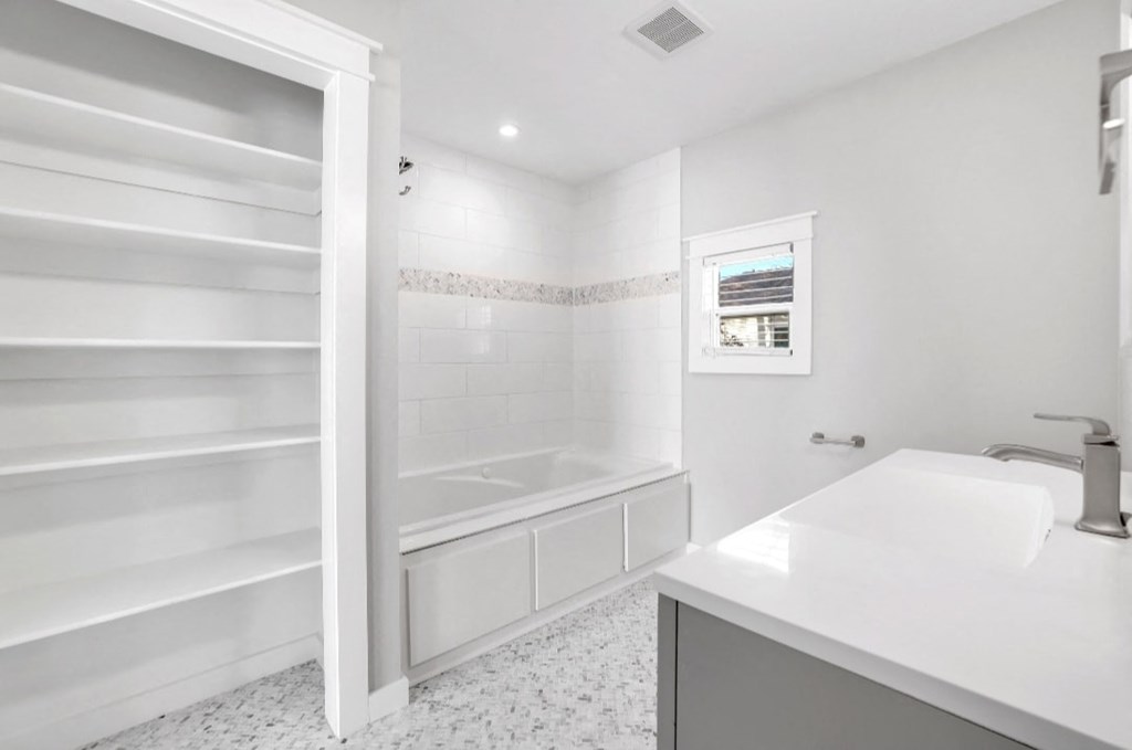 a white bathroom with a tub and a sink