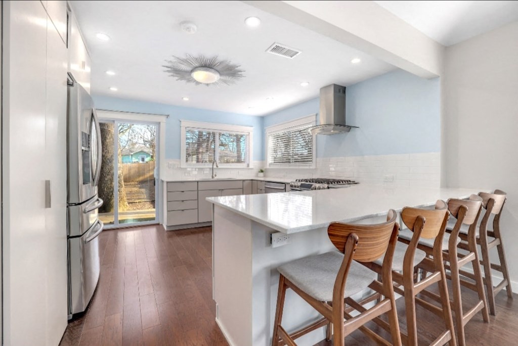 a kitchen with a white counter top and wooden chairs