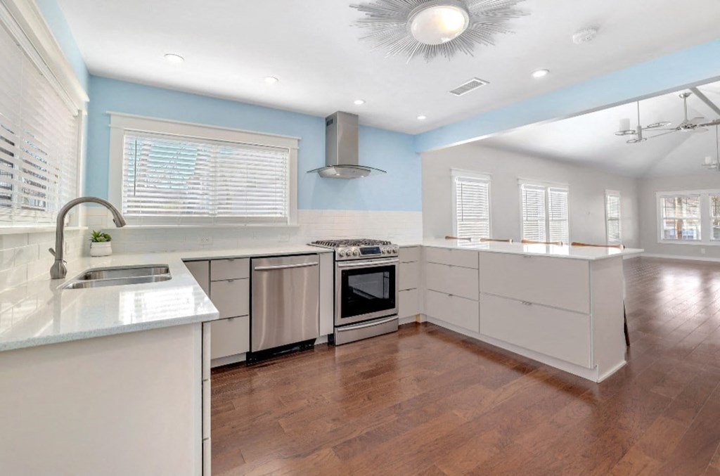 a large kitchen with white cabinets and a wood floor