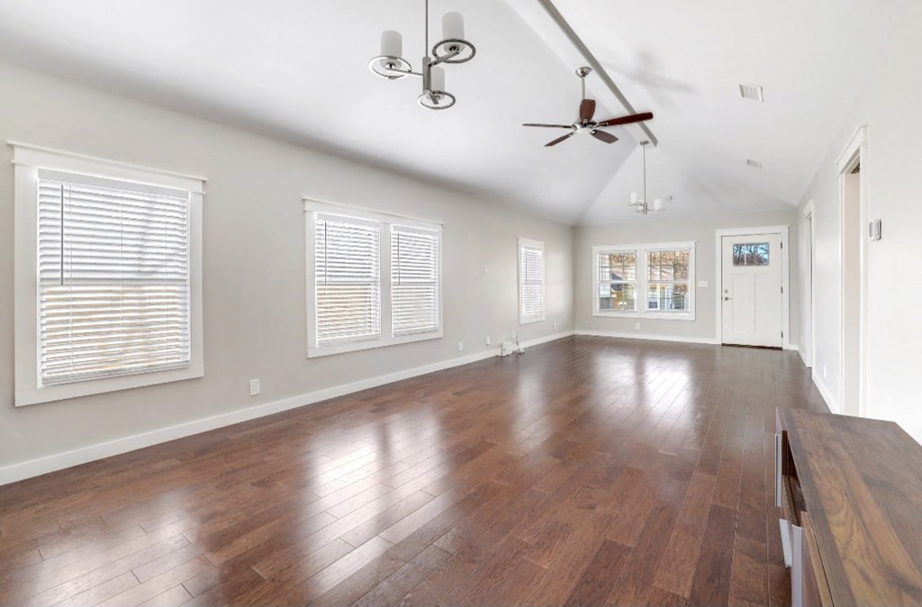 an empty living room with wood floors and a ceiling fan