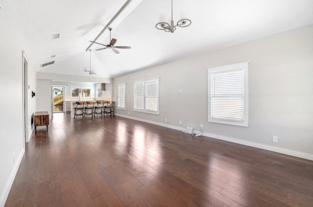 the living room and dining room of a house with wood floors and white walls