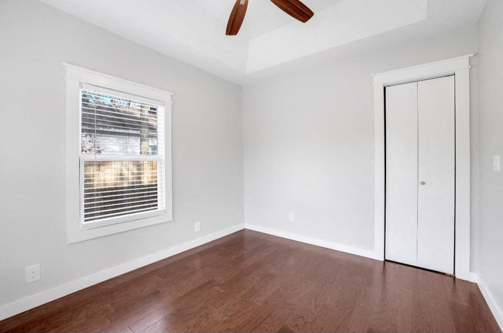 an empty room with wood floors and a window and a closet