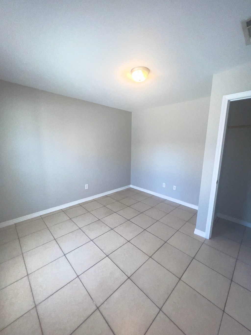 a empty living room with a tiled floor and gray walls