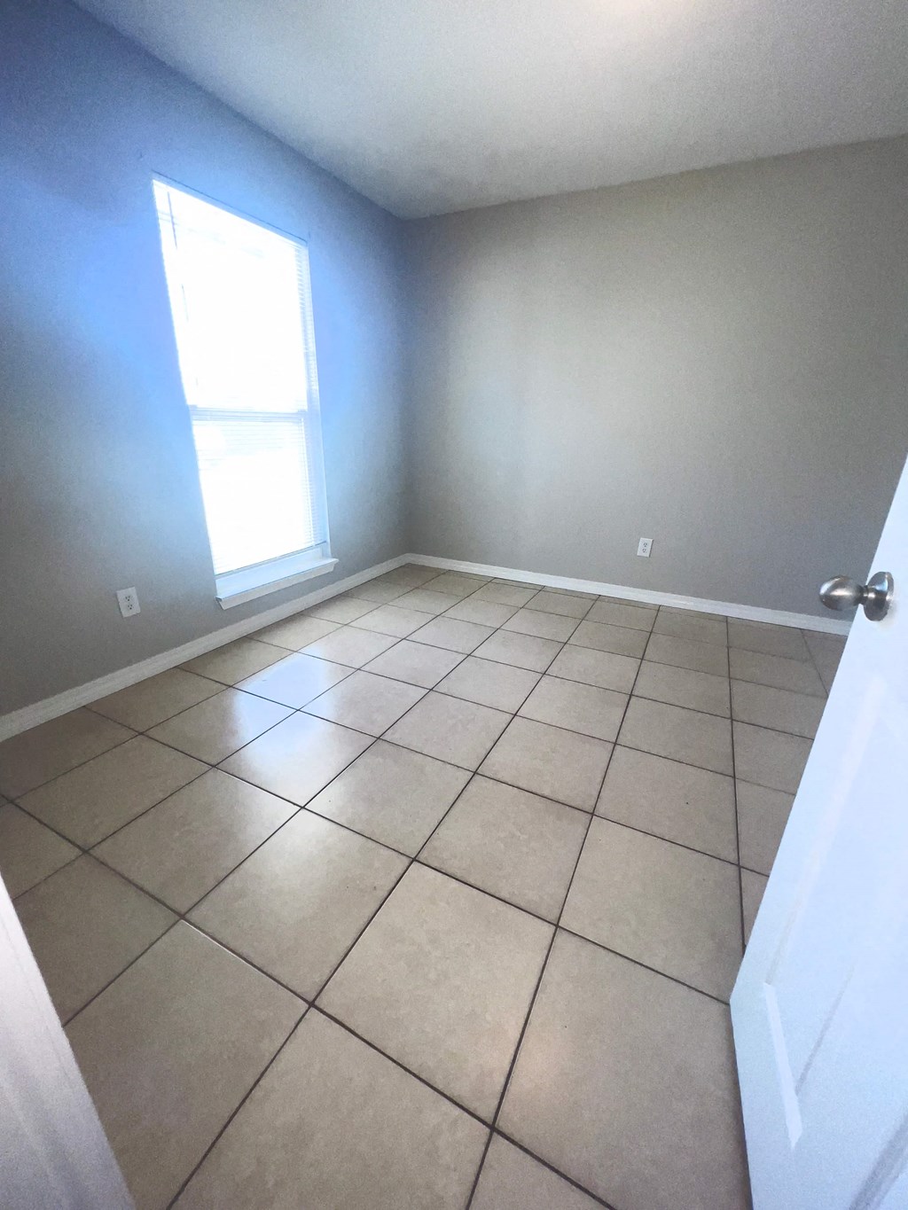 an empty room with a tiled floor and a window