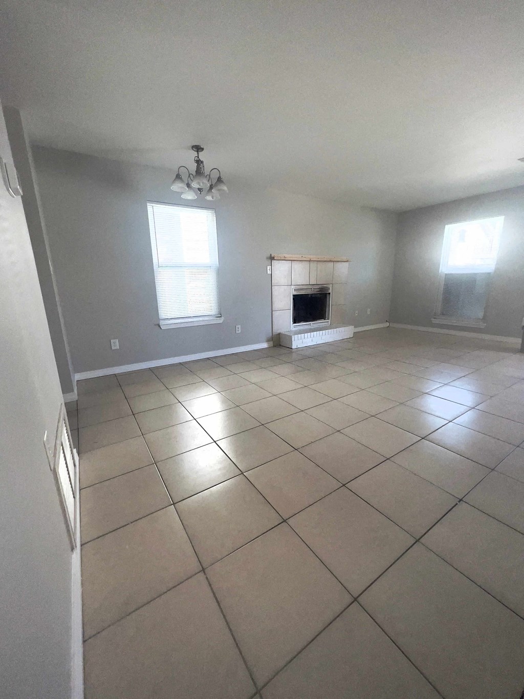 an empty living room with tiled floors and a fireplace