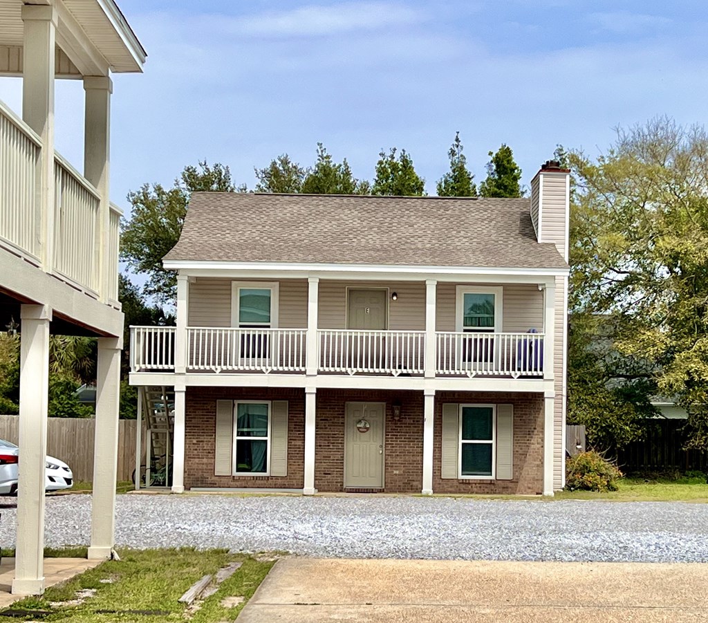 a white house with a balcony and a gravel driveway