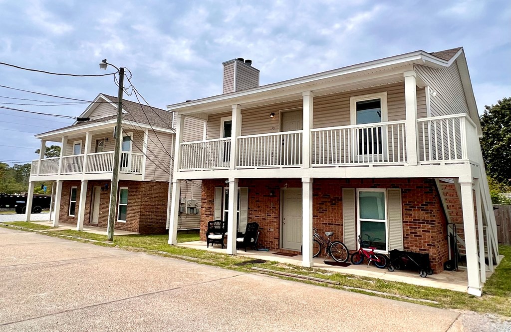 the front of a house with a porch and a balcony