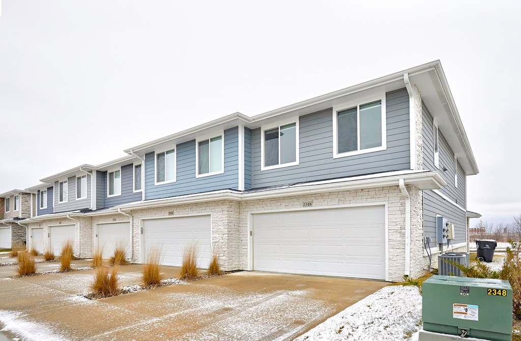 A row of houses with garages and driveways.