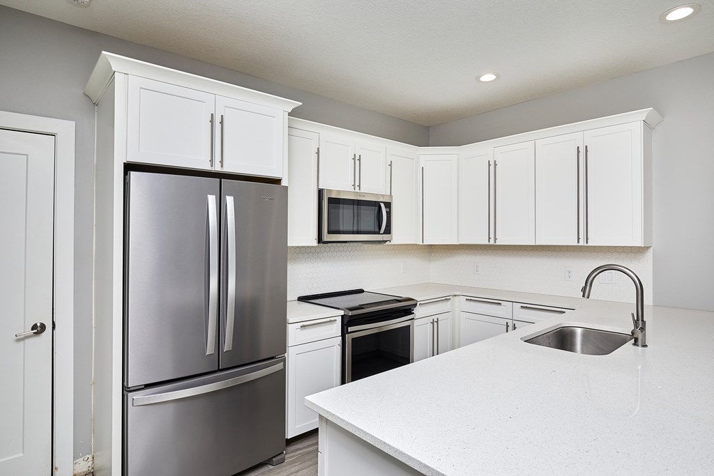 A kitchen with white cabinets and a stainless steel refrigerator.