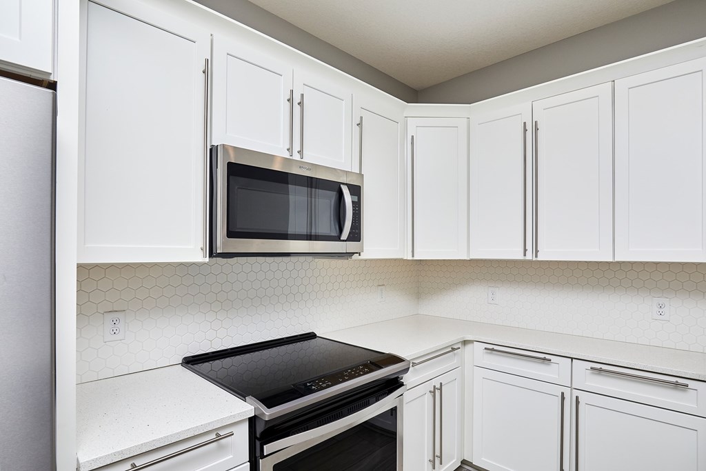 A kitchen with white cabinets and a black stove top oven.