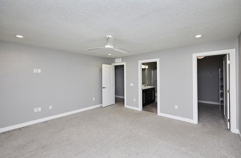 A spacious room with a ceiling fan and carpeted floor.