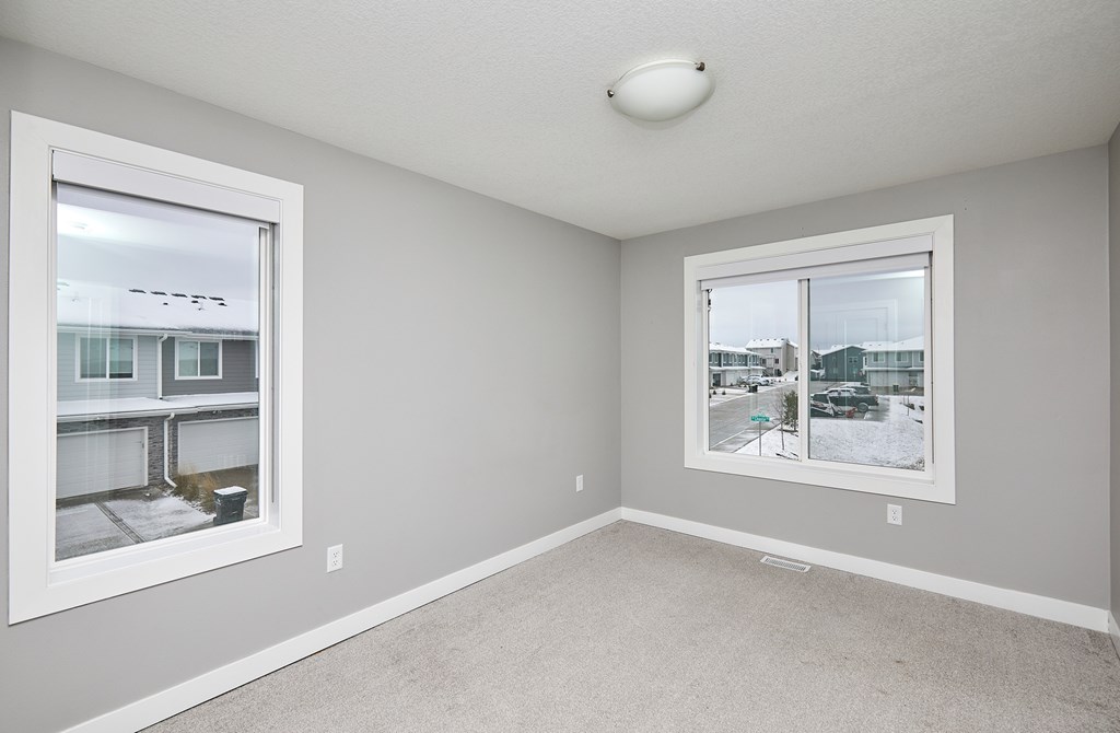 A room with two windows and a carpeted floor.