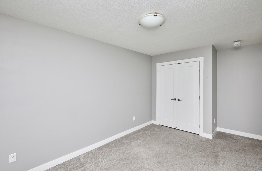 A room with a white door and carpeted floor.