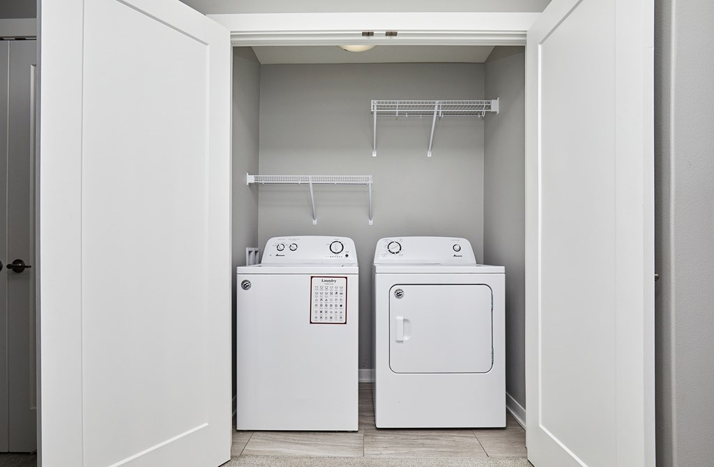 A white laundry room with two washing machines and a shelving unit.