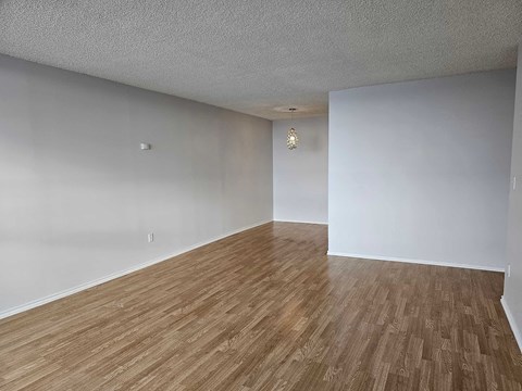 an empty living room with wood floors and white walls