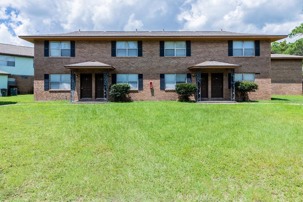 a large brick house with a lawn in front of it