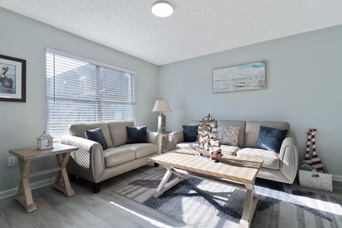 A living room with a white couch, a wooden coffee table, and a painting on the wall.