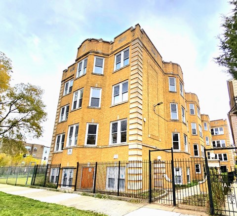 A large brick building with a black fence in front.