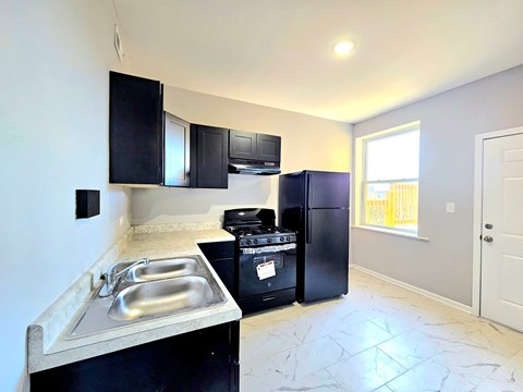 A kitchen with black appliances and a marble floor.