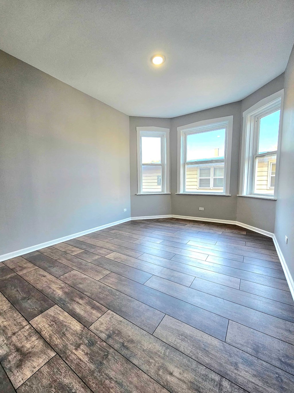 an empty living room with a large window and wood flooring