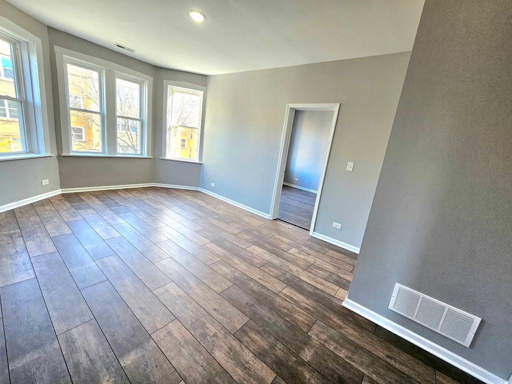 an empty living room with hardwood floors and a window