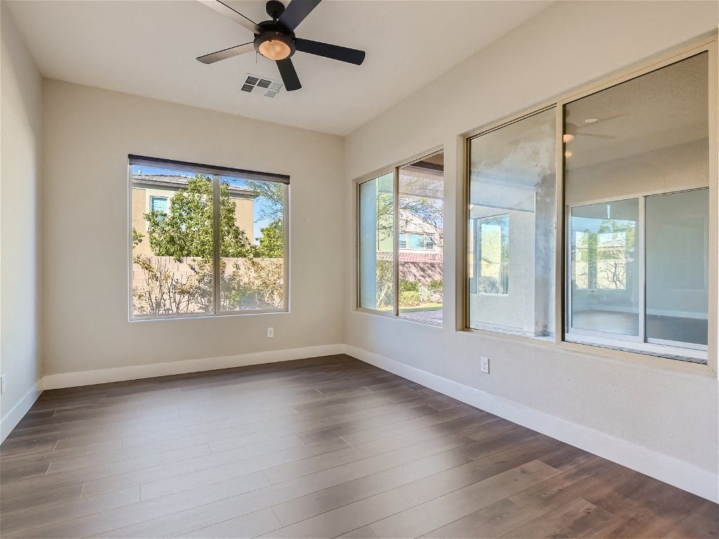 an empty living room with a ceiling fan and windows