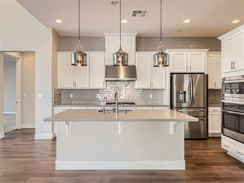 a white kitchen with a large island and stainless steel appliances