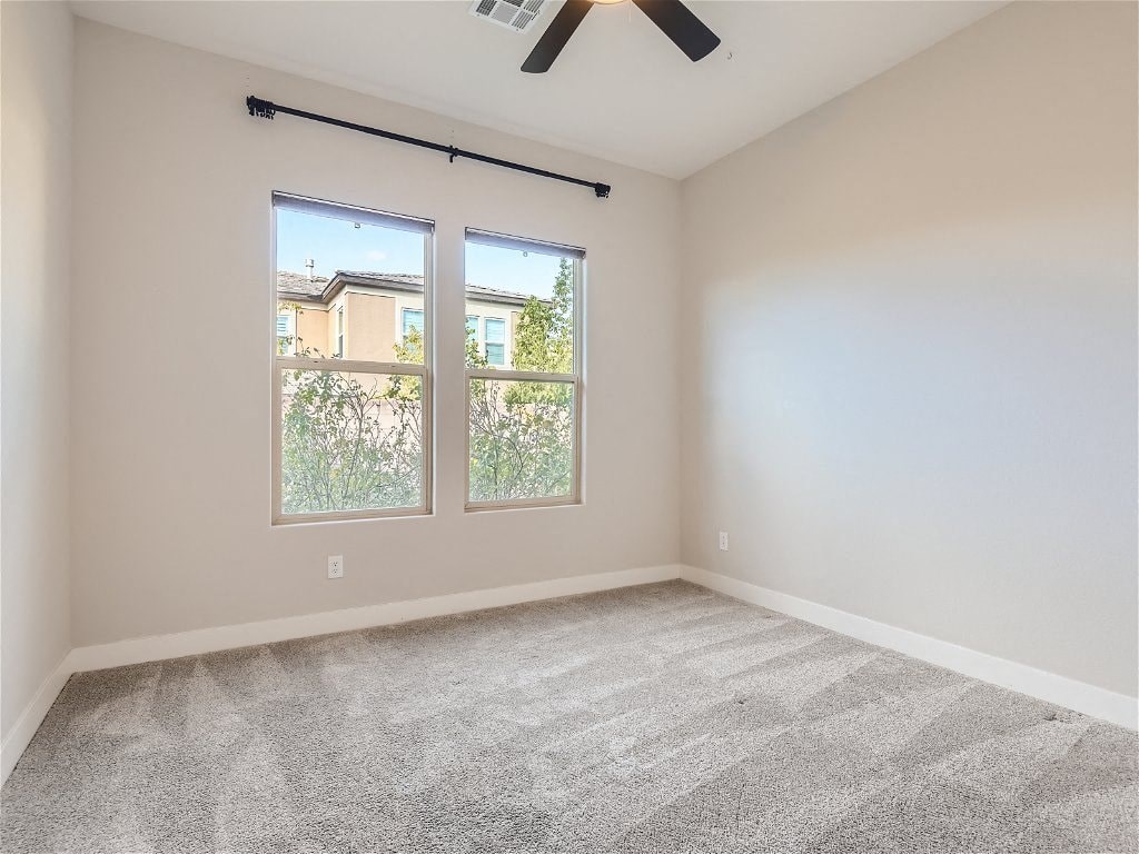an empty living room with two windows and a ceiling fan