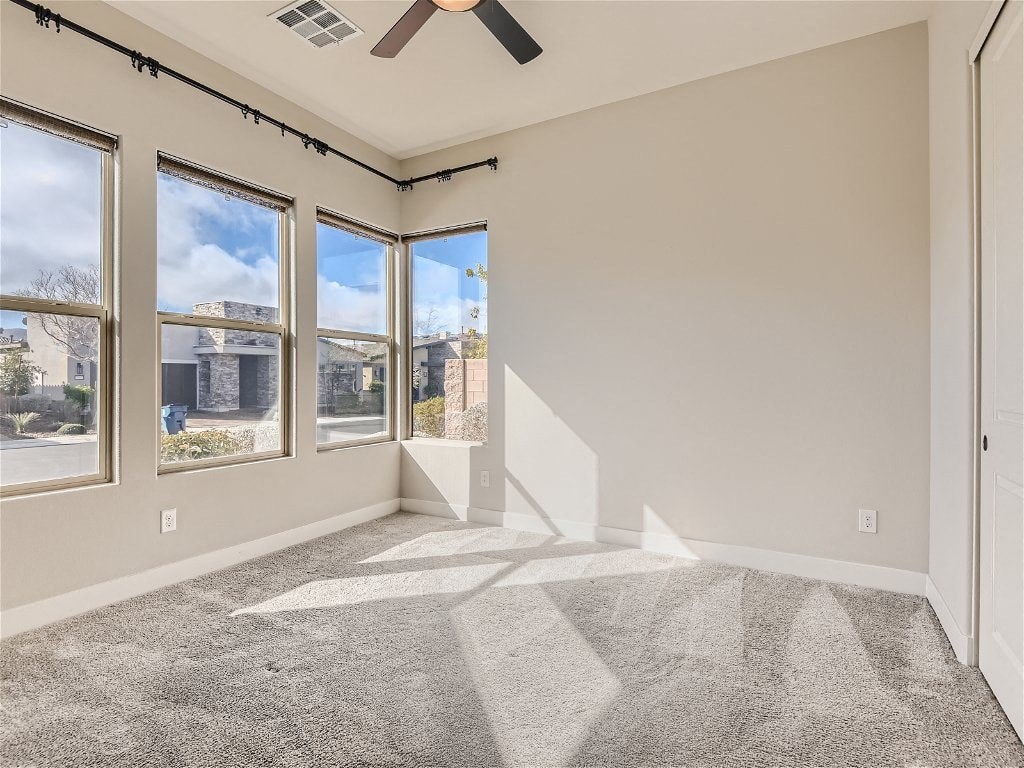 an empty living room with three windows and a ceiling fan