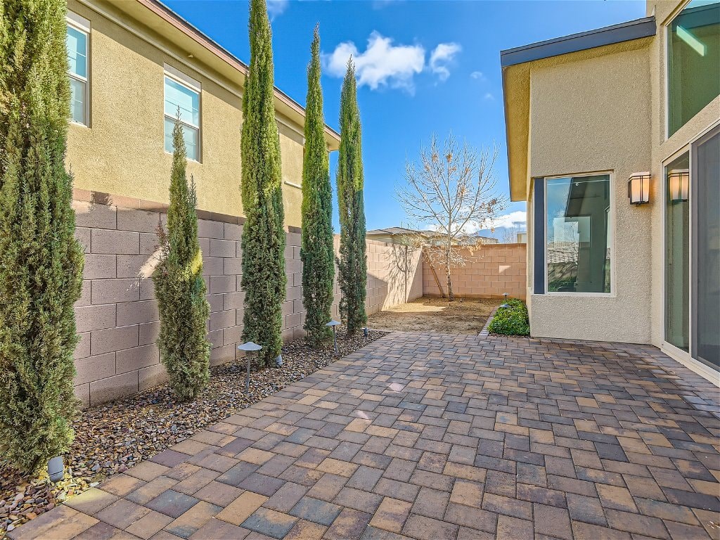 a brick pathway in front of a house with trees