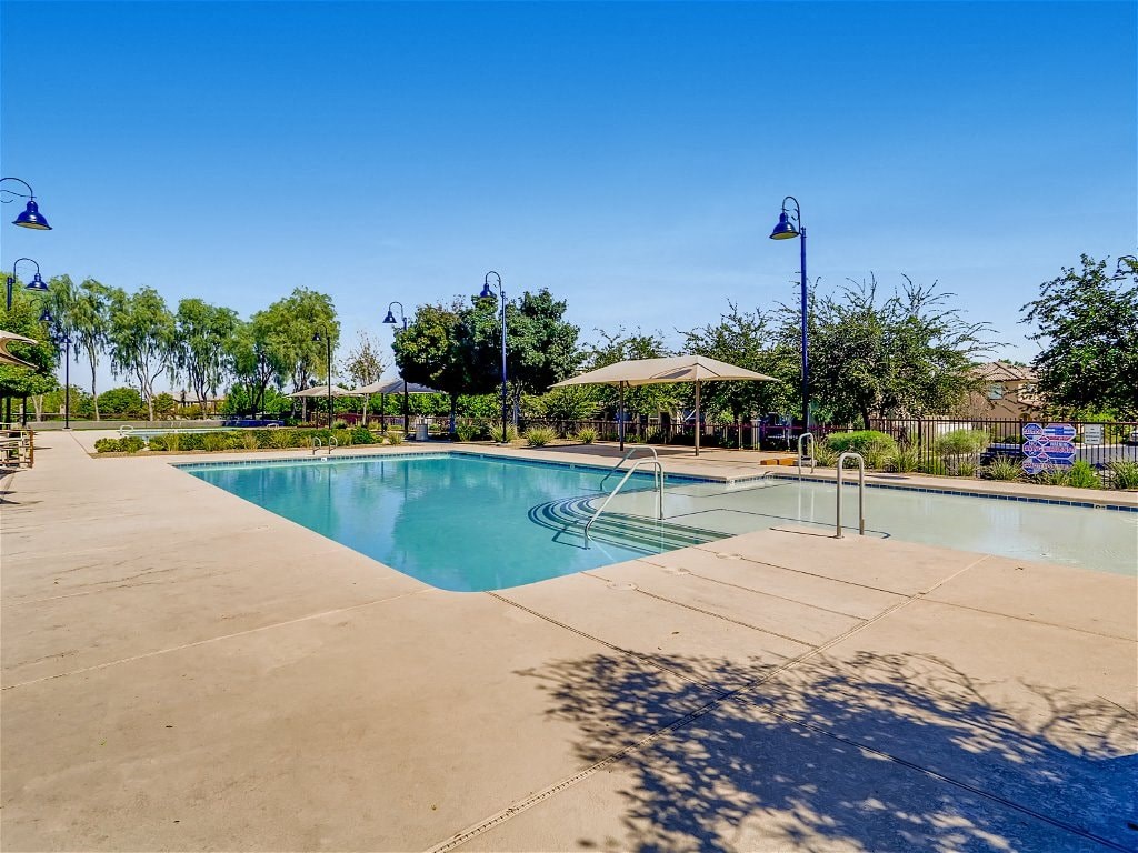 a swimming pool with trees and umbrellas next to it