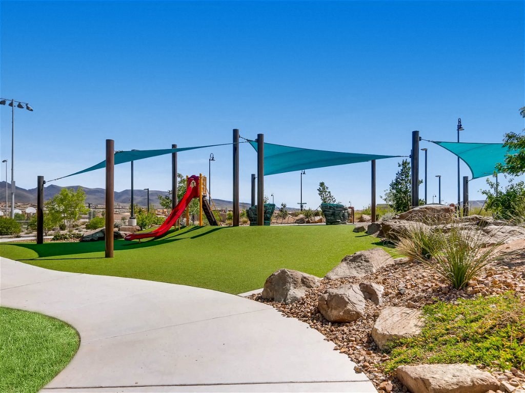 a playground with a swing set and green grass and rocks