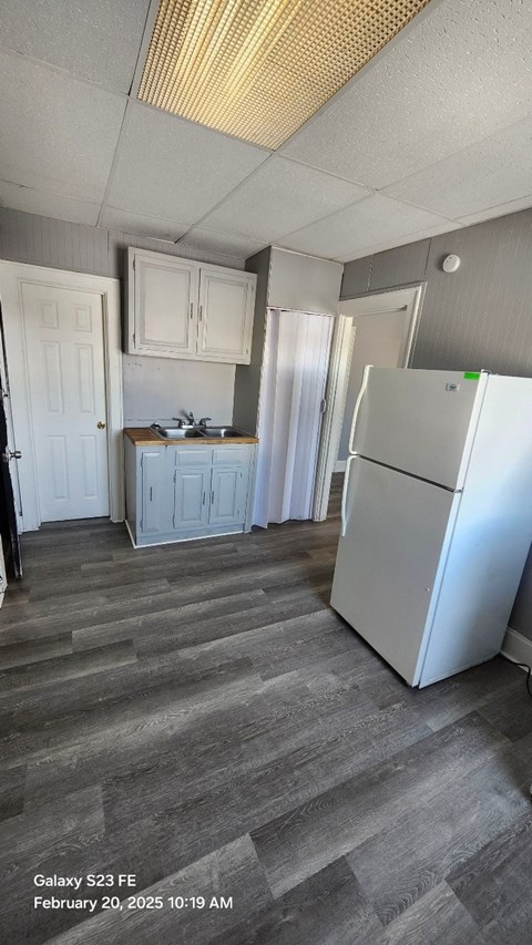 A kitchen with a white refrigerator and wooden cabinets.