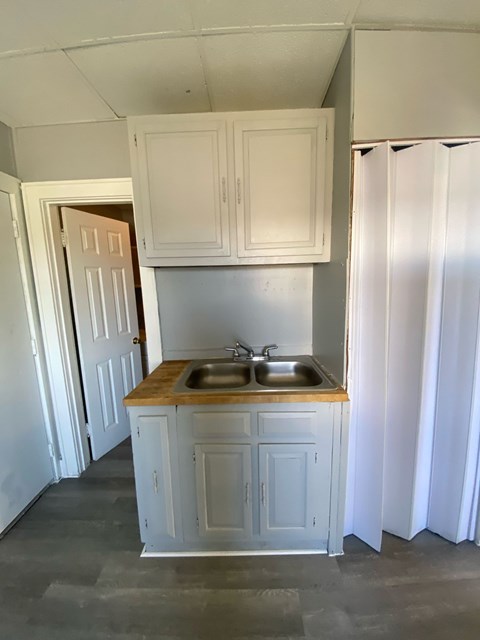 A kitchen with white cabinets and a wooden countertop.