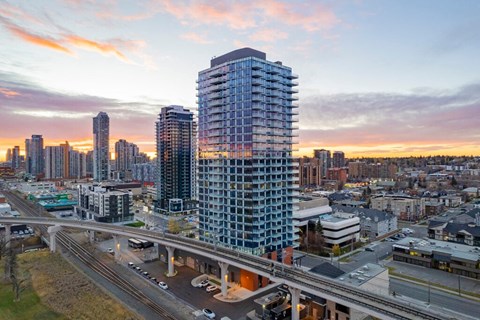 A modern high-rise building is the focal point of a bustling cityscape at dusk.