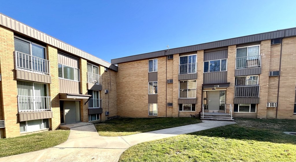 an exterior view of an apartment building with a sidewalk and grass