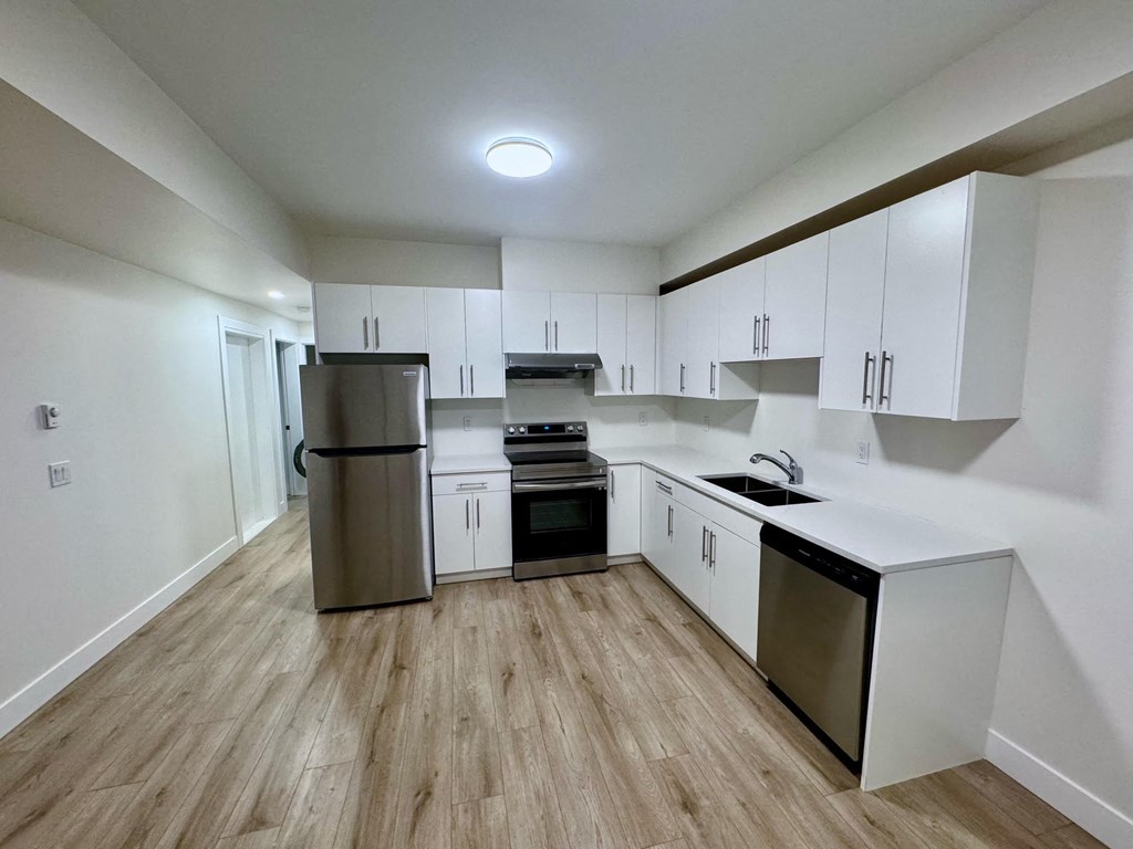 an empty kitchen with white cabinets and stainless steel appliances