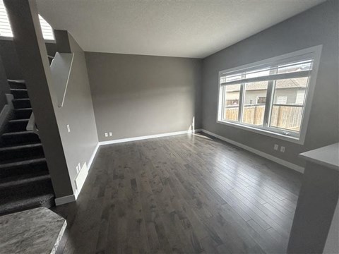 an empty living room with wood floors and a large window