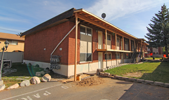 the front of a brick building with a porch and a satellite dish on the roof
