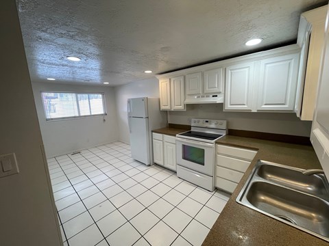 A kitchen with white cabinets and a white refrigerator.