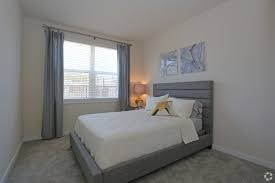 A bedroom with a large bed and a window with curtains.