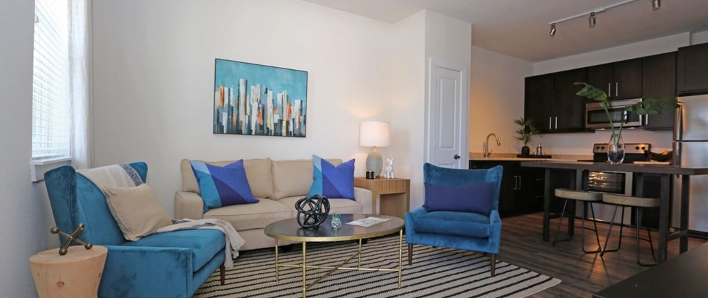 a living room and kitchen with a couch and chairs