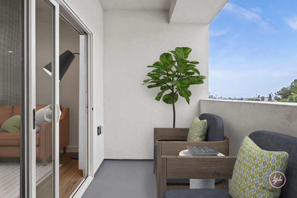 a balcony with a couch and a potted plant and a door to a bedroom