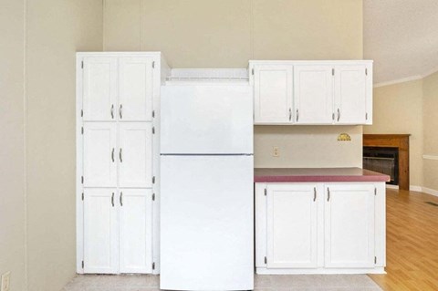 an empty kitchen with white cabinets and a white refrigerator