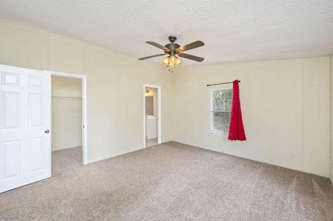 an empty living room with a ceiling fan and a red curtain